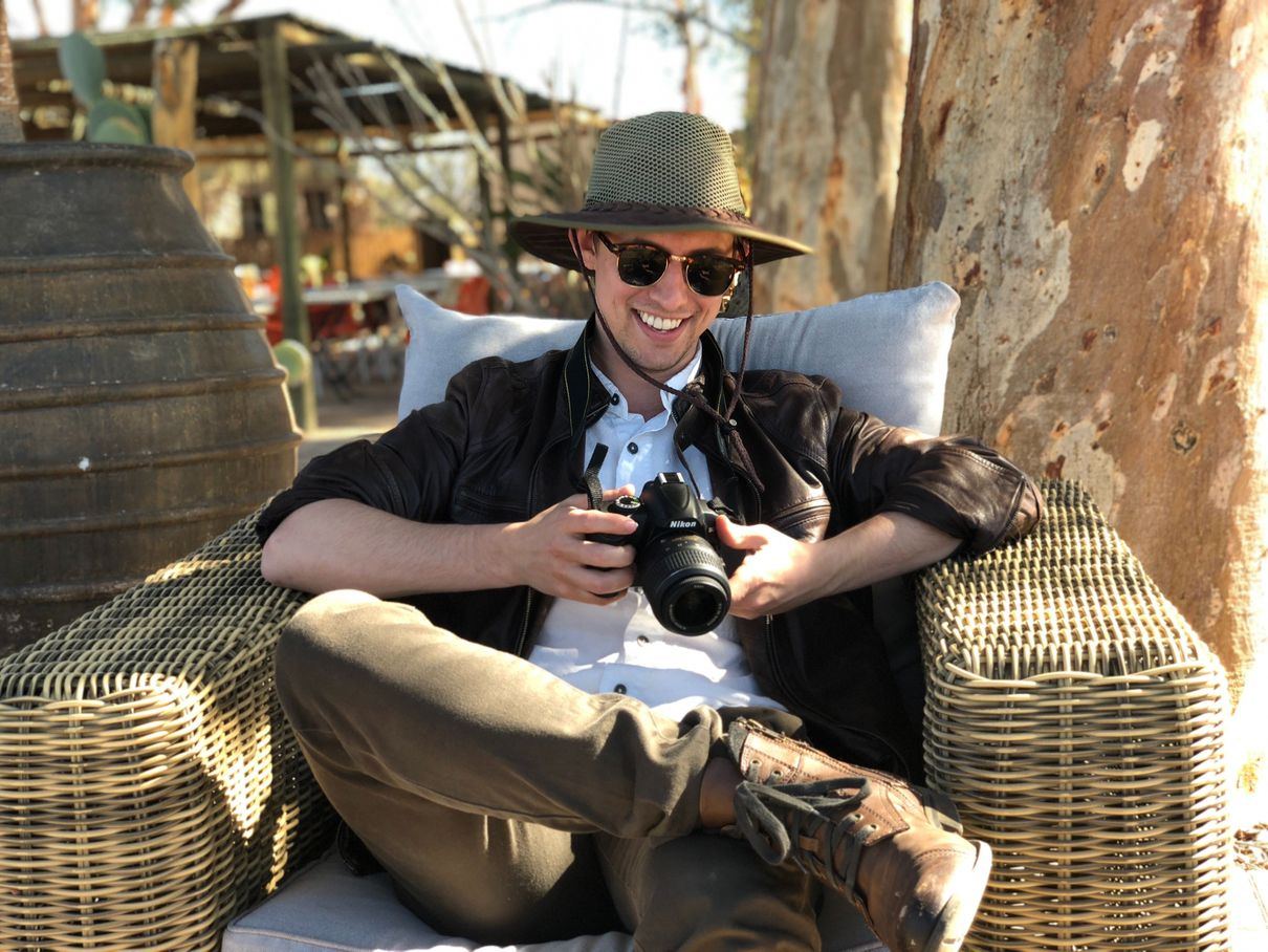 A man sitting on a chair while holding a camera