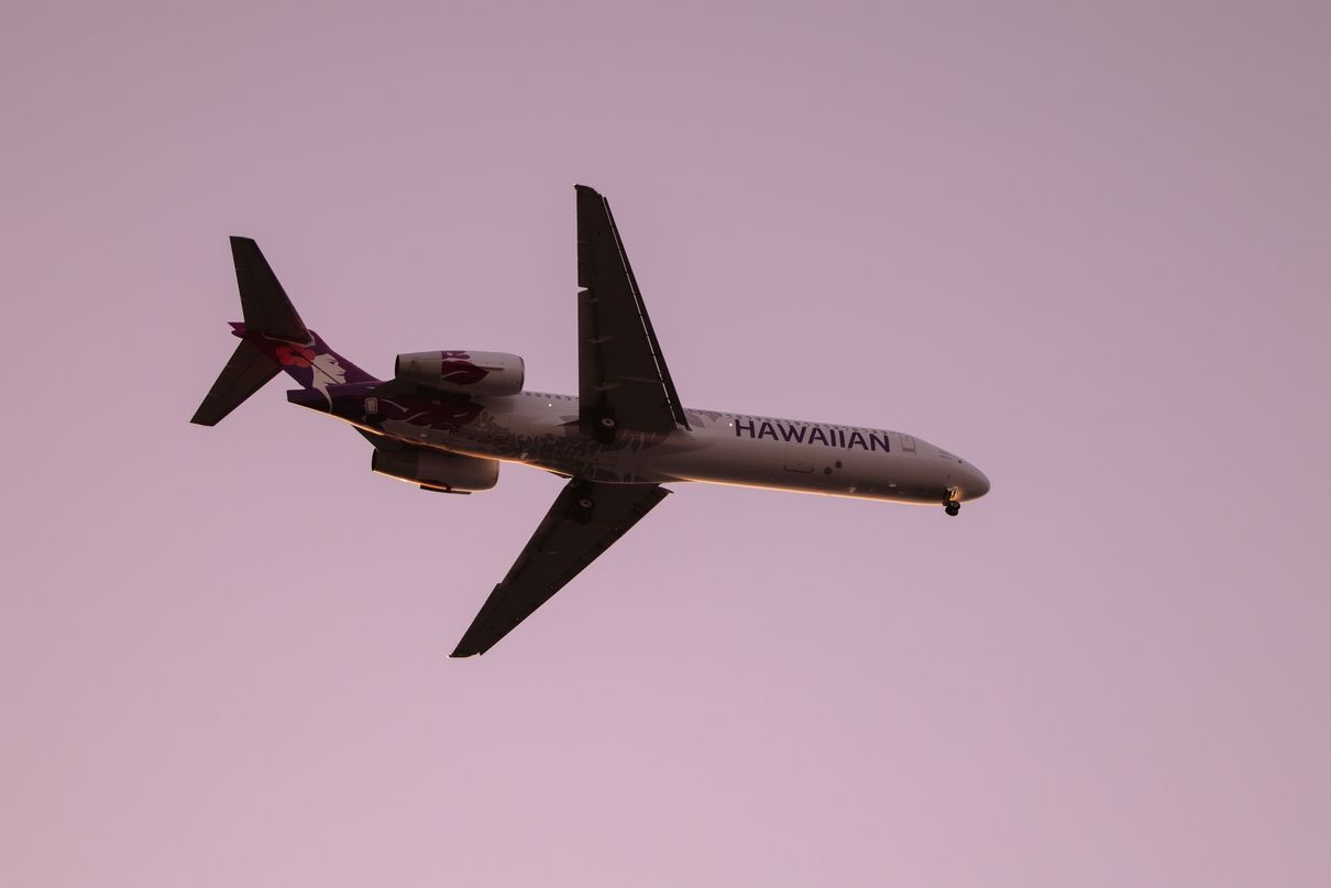 Airplane flying in the air with a pink sky background.