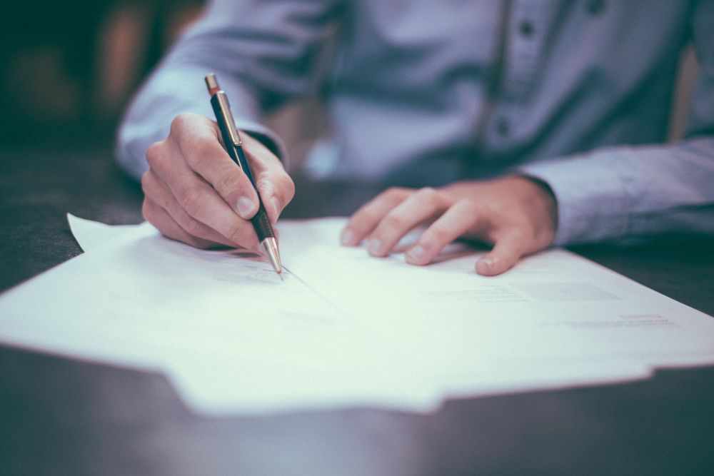 Person signing paper work with a pen