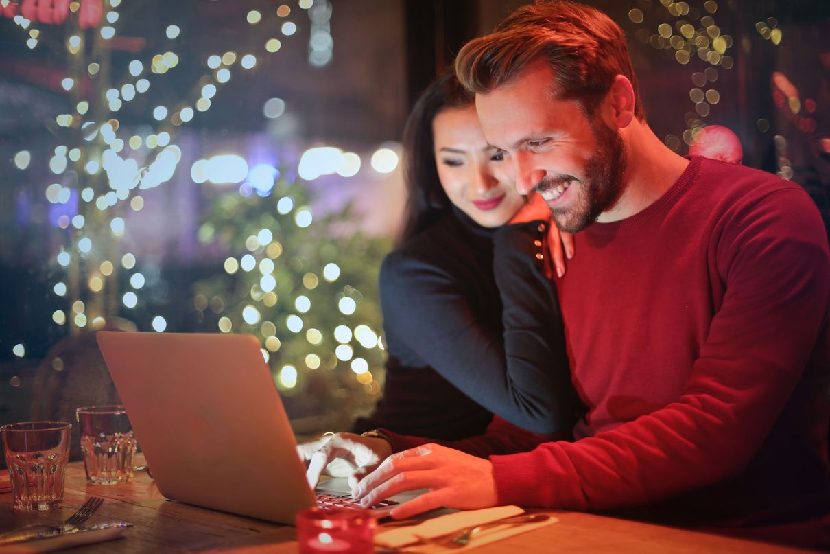 man and woman looking on silver laptop while smiling